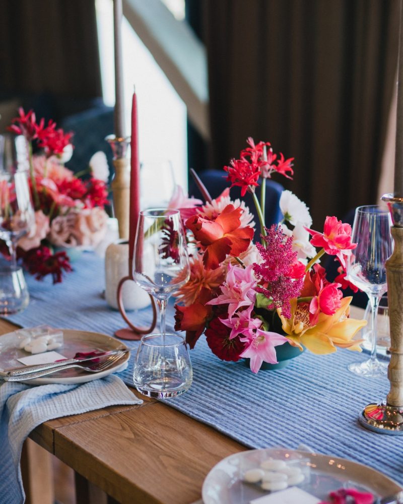 Coziness and style. Modern event design. Table setting at wedding reception. Floral compositions with beautiful flowers and greenery, candles, laying and plates on decorated table.